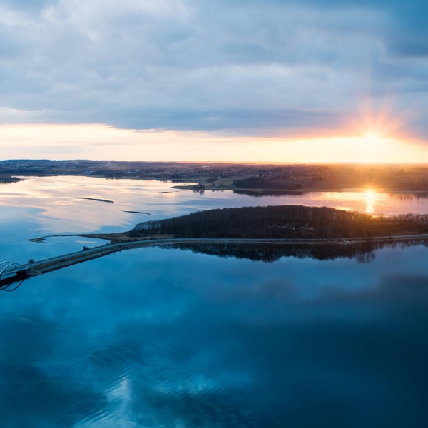 Droneoptagelse af bl&aring;t vand og solnedgang ved Munkholmbroen